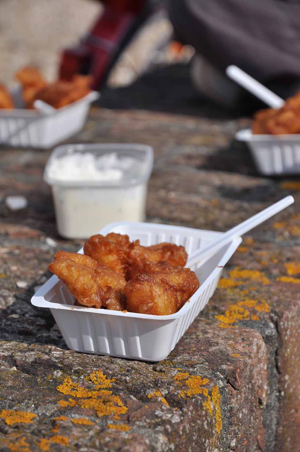 Fried fish in a white plastic bowl.