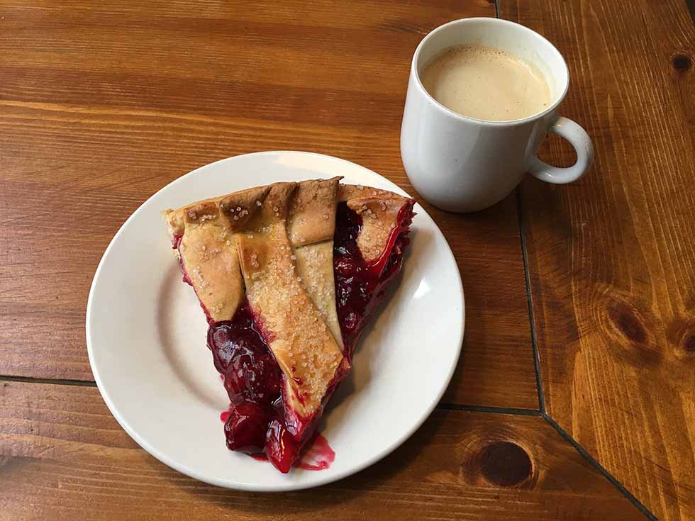 Dutch Limburgse vlaai on a white plate and a mug filled with coffee