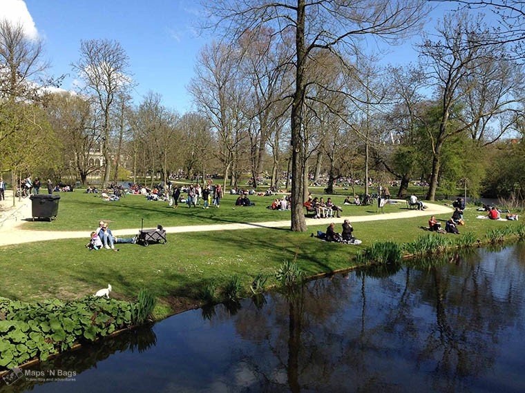 People chilling on the grass at the Vondelpark on a sunny day.