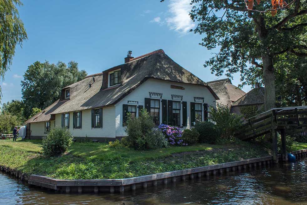 White cottage house and green garden in the fairytale village of Giethoorn.
