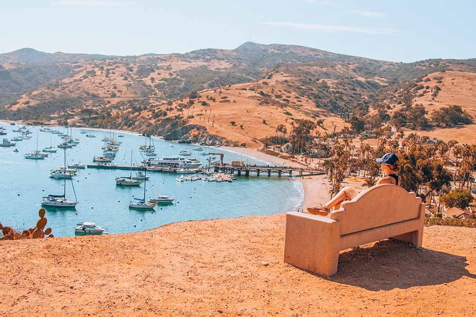 Blond woman sitting on a bench and watching over a lake in Santa Catalina, California