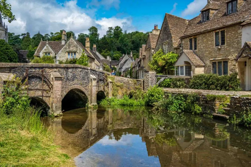 Blue skies and reflections in the picturesque Cotswold village of Castle Combe