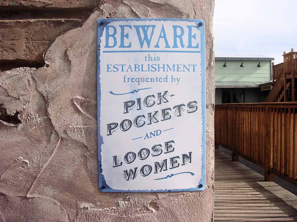 White board with blue letters warning about pick pockets and loose women outside a bar. #Travel #Scams