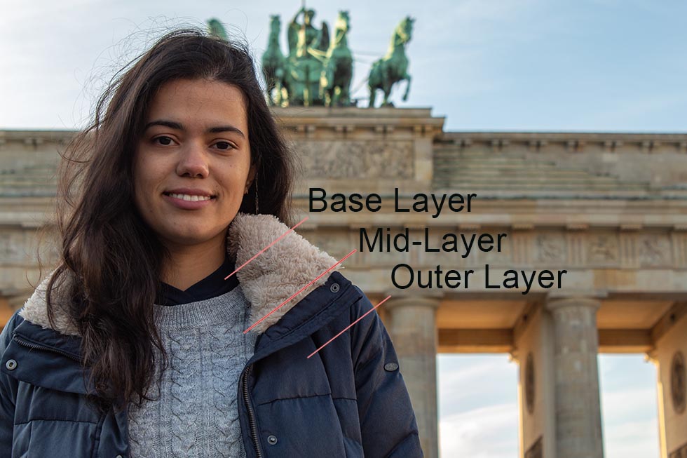 Brunette smiling in front of the Brandenburg Gate in Berlin.