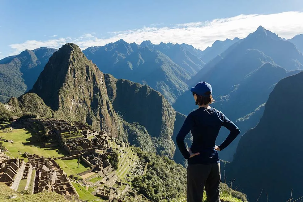 Woman wearing black clothes starring at Machu Picchu in Peru.