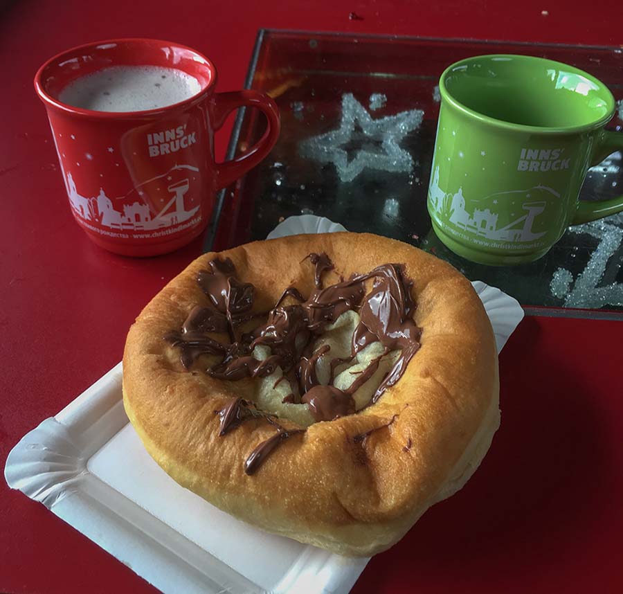 Chocolate on a piece of dough and two mugs on a red table in Innsbruck