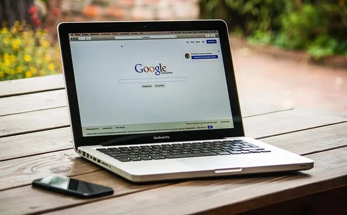 A mac book pro on a table with Google search open in the browser