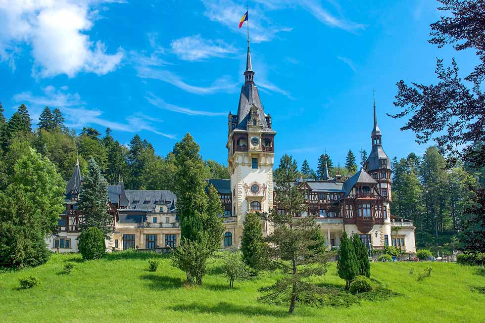 Green grass in front of the Peles Castle in Romania in a sunny day.