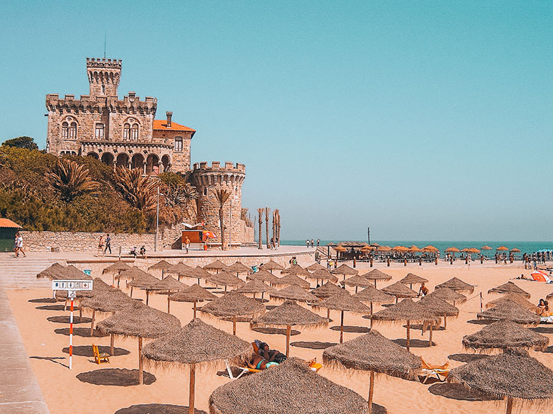 Castle near sun umbrellas at Tamariz beach in Estoril, Lisbon, Portugal