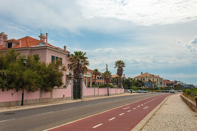 Bike path next to the street in Cascais in front of a pink house