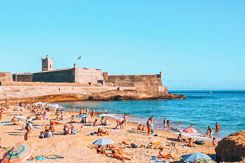 People laying at the Carcavelo beach in Lisbon near São Julião fort