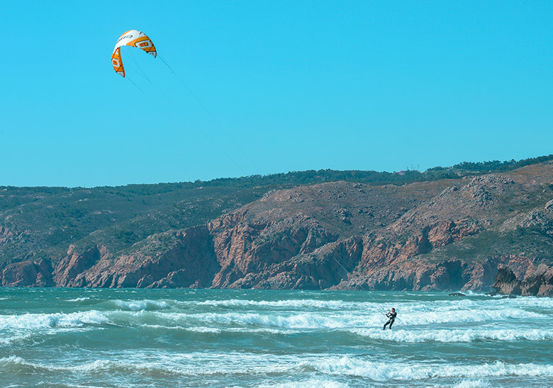 Man kitesurfing on a sunny and clear day at Guincho beach in Sintra, Portugal