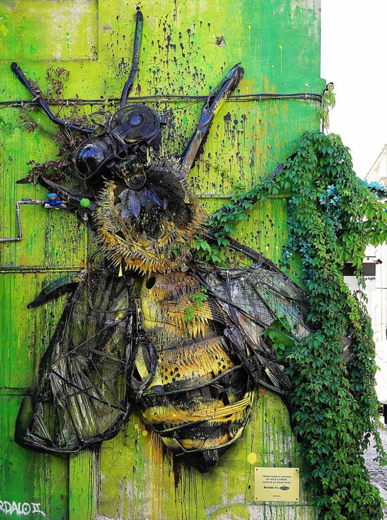 Wall art in Lisbon of a bee on a green wall