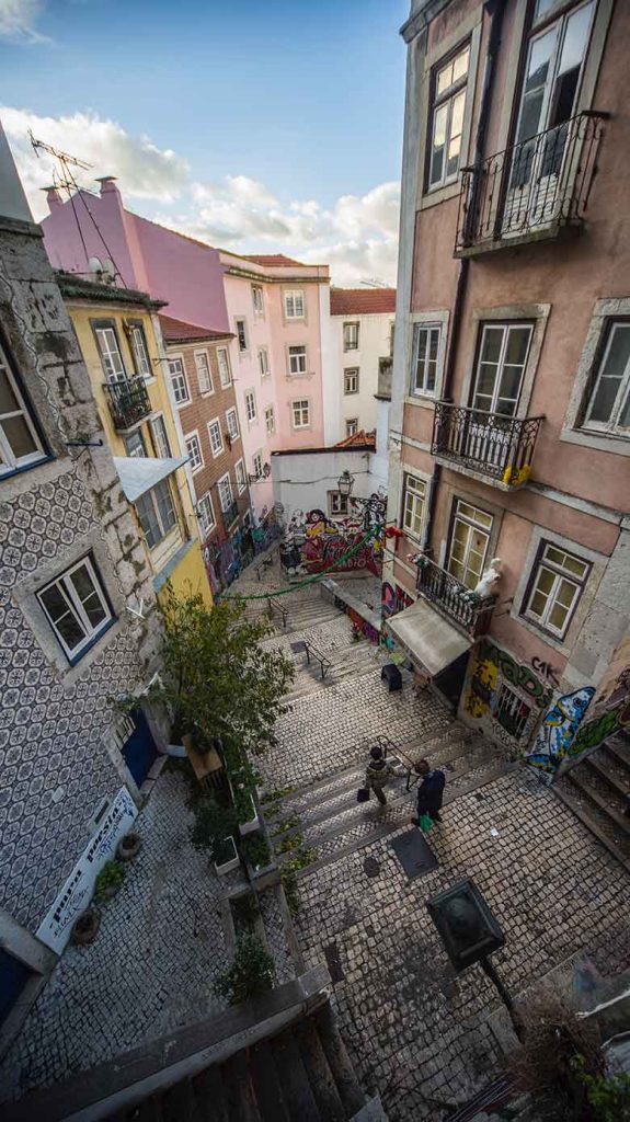 Two people walking downstairs in an alley covered in graffiti in Lisbon