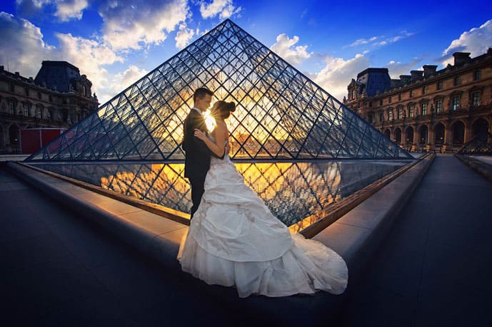 Is Paris the City of Love? A couple standing in front of the Louvre Museum in this romantic city.