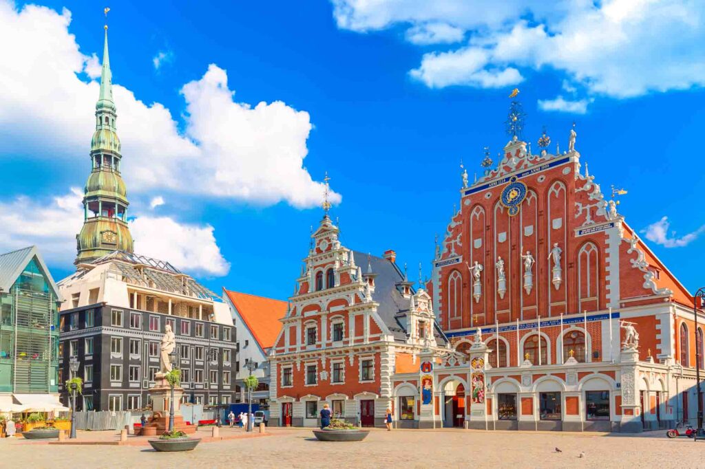 View of the Old Town Ratslaukums square, Roland Statue, The Blackheads House and St Peters Cathedral against blue sky in Riga, Latvia