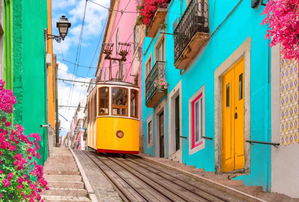 Yellow tram on a street with colorful houses and flowers on the balconies in Lisbon, Portugal
